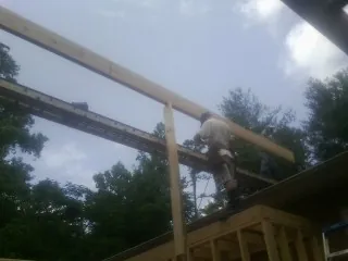 Carpenter setting a ridge beam over a new addition frame — Ice Dam Removal by Roofing Brothers in Walton